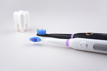 Modern electric ultrasonic toothbrush with rechargeable battery on a gray surface.