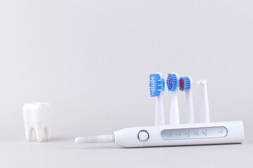 Modern electric ultrasonic toothbrush with rechargeable battery on a gray surface.