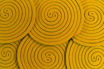 The arrangement of mosquito coils colored gold oil painted creates a distinctive, repeating circular pattern spiral background, resembling a yin-yang symbol