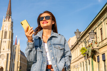 Low angle view of city woman with smartphone in hand on background of city street