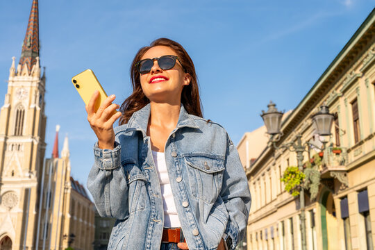 Low angle view of city woman with smartphone in hand on background of city street