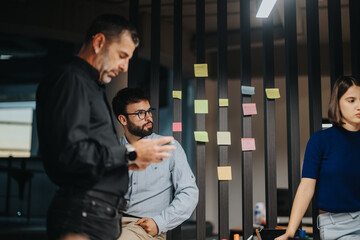 Group of business professionals collaborates in a modern office, using post-it notes for...