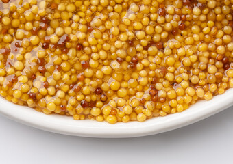 French Dijon mustard in a metal spoon, top view on mustard grains background. Gastronomy concept,...