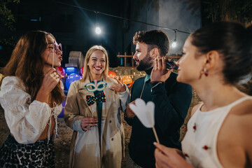 A joyful gathering of friends in a backyard setting, wearing playful masks and enjoying the festive outdoor ambiance illuminated by string lights.