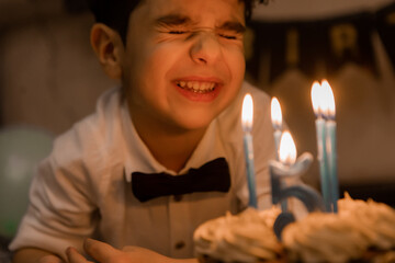 little boy makes a wish and blows out the candles on his birthday cake