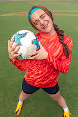 Sporty girl holding a soccer ball in her hands. Girl soccer player at soccer training. Soccer.