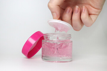 make up container with pink lid and white between the lid and a pink gel product or cream and a hand showing the product
