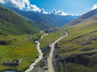 Breathtaking aerial view capturing a winding road through a vibrant green valley, alongside a...