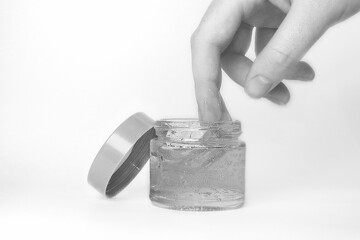 make up container with lid and gel product or cream and hand showing product
