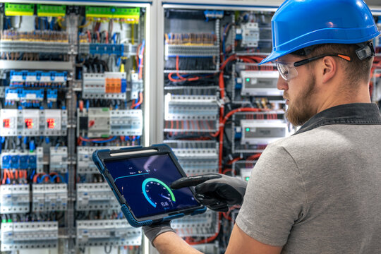 Electrician with tablet. Speed testing. Digital switchboard monitoring.