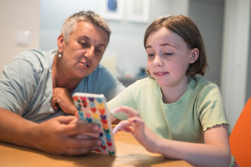 Smiling caucasian grandmother and  granddaughter enjoying time together with smartphone. 