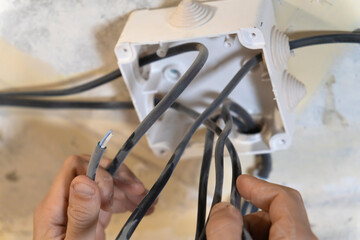Electrician is working on electrical wiring, carefully connecting wires to a junction box during a home renovation or installation project