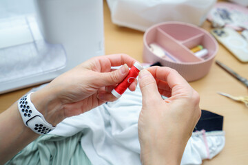 Sewing expert carefully prepares red thread for stitching on fabric at a well-organized crafting workspace