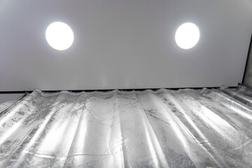 Modern interior design featuring elegant silver curtains hanging from a ceiling-mounted rail, with spotlights providing soft illumination, creating a stylish and contemporary ambiance