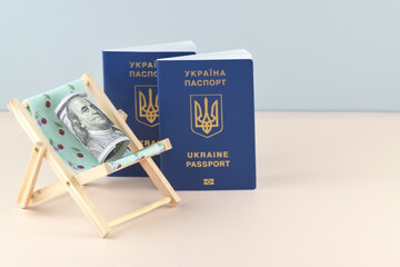 Ukraine passport and chaise lounge with dollars and globe on a light background.