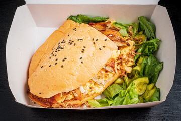 A delicious grilled chicken sandwich with fresh lettuce and pickles served in a takeout box