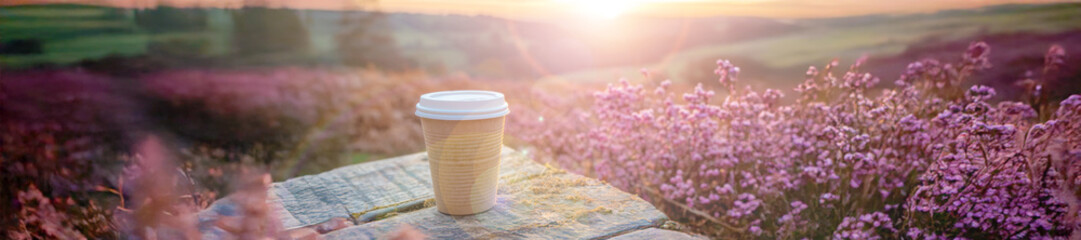  A tumbler with cap stands on an old wooden table in the morning.