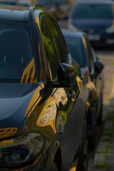 A long row of various cars is currently parked along the side of the road, creating a distinct line...