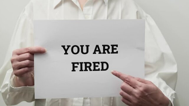 person holding a sign with bold you are fired