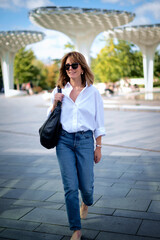 Full length of a happy mature woman walking in the city on a summer day
