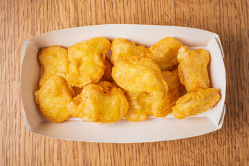 Delightful and crispy nuggets arranged neatly in a white box on a warm wooden table