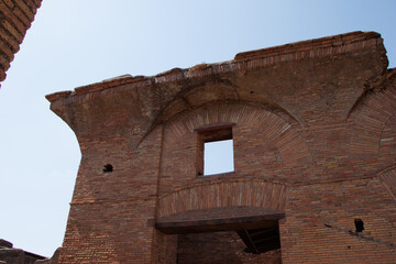 Ancient brick structure with arched windows and weathered walls under a clear blue sky