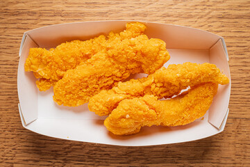 Scrumptious chicken tenders coated in crispy breading are served in a simple white box