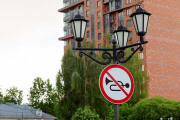 The sign prohibits the use of a horn, installed on a rare lamppost in a cozy courtyard of a...