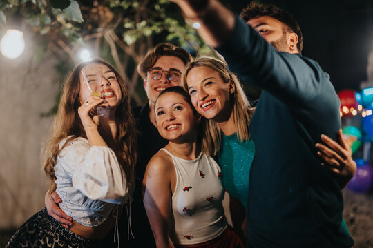 Group of friends sharing a happy moment, socializing and celebrating during an evening event outdoors.