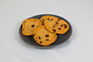 A plate of delicious chocolate chip cookies offers a tempting treat, perfect for snacks or desserts. The fresh baked treats are on a grey plate.
