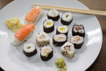 different types of sushi, served on a white place with chopsticks,