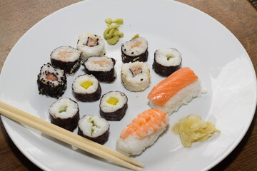 different types of sushi, served on a white place with chopsticks,
