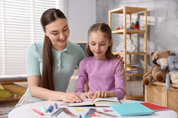 Dyslexia. Mother and her daughter reading book at table indoors