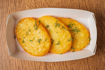 A platter displays four perfectly fried fritters topped with vibrant green dill