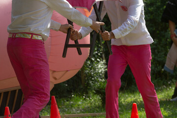 Two individuals dressed in vibrant pink pants are enthusiastically playing a fun game using...