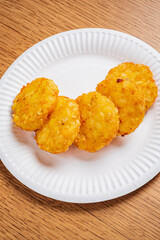 A plate holds several golden, crispy potato rounds, perfect for snacking at any event