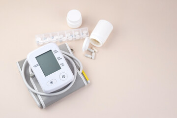 Digital blood pressure tonometer and pack of pills on a light background with copy space.