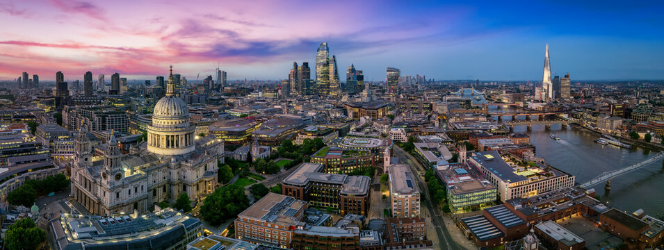 Panoramic aerial view of the illuminated London skyline, from the City and St. Pauls Cathedral to London Bridge, during evening time - Powered by Adobe