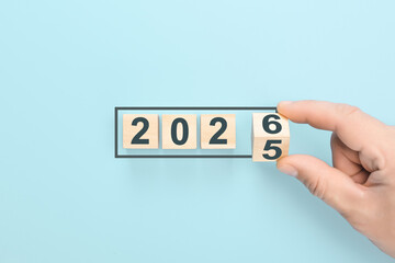 Hand turning last wooden block to complete 2026, changing year from 2025, concept of new year's eve countdown