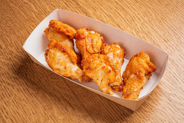 Golden crispy chicken wings arranged neatly in a paper tray, ready for enjoyment at a gathering