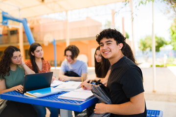 Happy high school student studying with friends in schoolyard