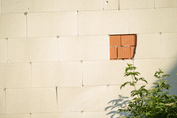 A white brick wall that features a noticeable hole within it, adding an interesting architectural...