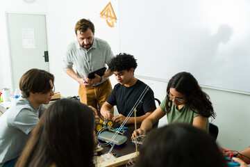 High school students building electronics project with teacher supervising
