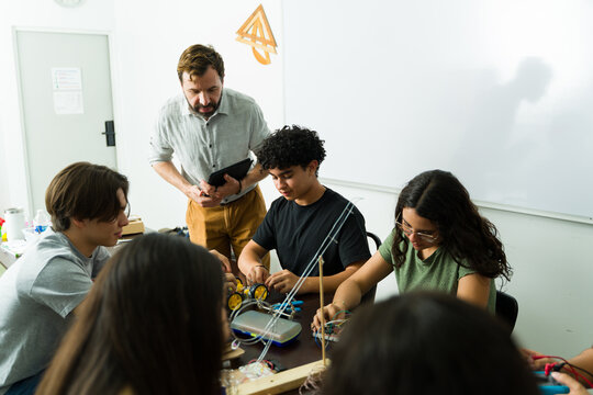 High school students building electronics project with teacher supervising