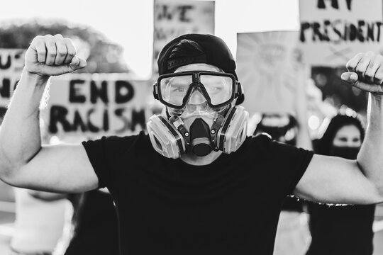 Multiracial immigrants protesting outdoor against government laws - Riot, demonstration and activist concept - Main focus on center man mask - Black and white editing