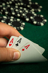 A player holds three aces in their hand while surrounded by poker chips on a green felt table. The excitement of the game is palpable as bets are placed
