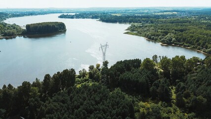 Electricity transmission tower by lake and forest