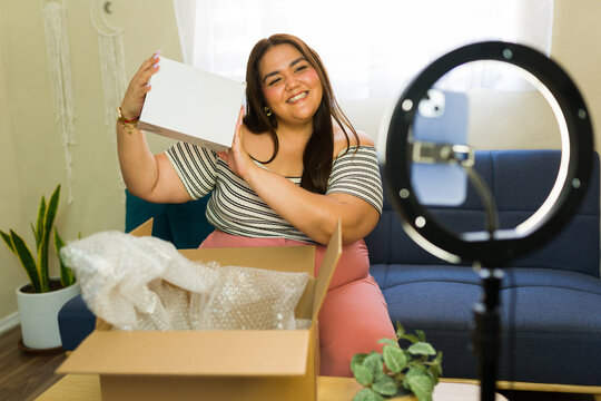Plus size influencer unboxing product while recording video blog - Powered by Adobe