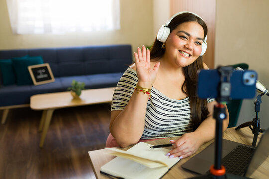 Latin content creator waving and recording a video blog from home