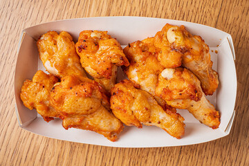 Golden brown chicken wings perfectly fried, served in a convenient takeout box for sharing